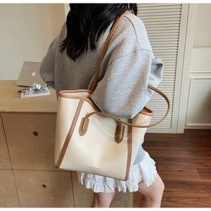Detail of cream-white tote bag with brown leather trim and retro letter print