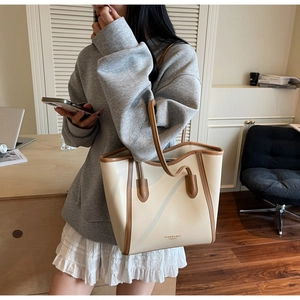 Detail of off-white tote bag with brown trim and FASHION & BAGS logo on model