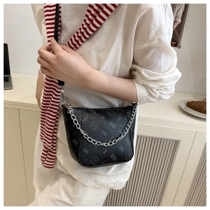 Close-up of black leather crossbody bag featuring cat prints and silver chain strap