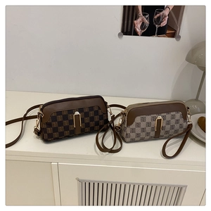 Detail of crossbody bags with checkerboard pattern and golden metallic hardware on desk