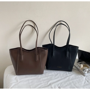 Detail of high-capacity tote bags in brown and black leather with modern office props