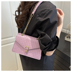 Détail de la texture tressée violette du sac avec boucle dorée et bandoulière en chaîne