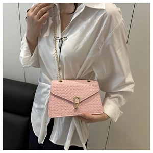 Détail du sac bandoulière rose tissé avec fermoir en métal doré et bandoulière chaîne