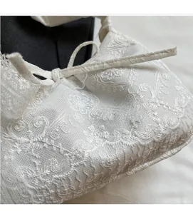 Close-up of white crochet lace fabric featuring floral patterns and a soft bow tie detail