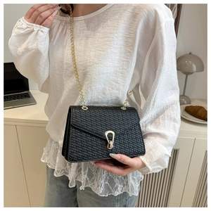 Détail du sac bandoulière noir tissé avec boucle fer à cheval dorée sur haut en dentelle