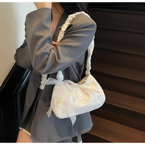Detail of white lace tote bag featuring floral embroidery and ribbon bow accents