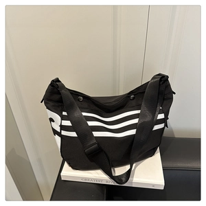Gros plan détaillé du grand sac bandoulière en nylon noir avec des rayures blanches