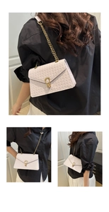 Gros plan sur un sac bandoulière tissé rose pâle avec boucle fer à cheval dorée et chaîne