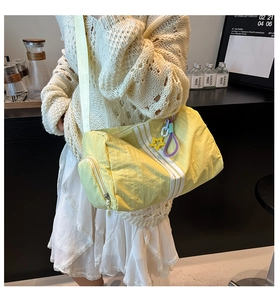 Detail of yellow nylon barrel bag with sporty white stripes and star charm on shoulder