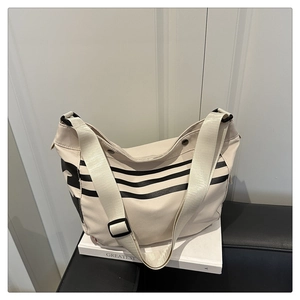 Détail d'un sac hobo en toile beige avec rayures noires et bandoulière large réglable