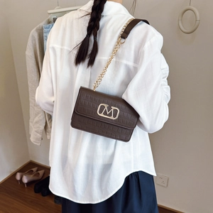 Bolso bandolera marrón oscuro con relieve de cocodrilo, logo M dorado y correa de cadena