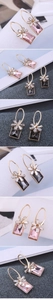 Detail of elegant gold earrings with pink rectangular gemstone and bow-shaped crystal design