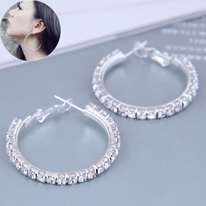 Detailed view of 60mm silver hoop earrings with clear rhinestones on model