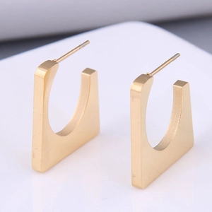 Detailed view of gold cube earrings showing brushed metallic texture and geometry