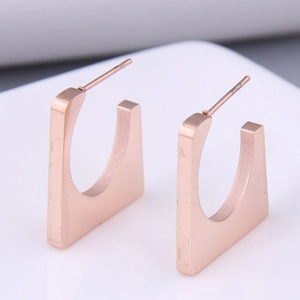 Close-up of geometric square titanium steel earrings in rose gold finish with metal studs