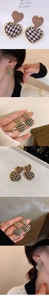 Macro detail of red heart apple earrings with houndstooth pattern and gold metal frame