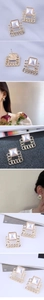 Detailed view of geometric square earrings with faux pearl and gold chain link frame