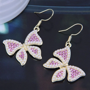 Detailed macro shot of butterfly earrings with pearls and pink rhinestones on gold base