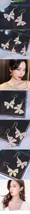 Detail view of butterfly drop earrings with sparkling rhinestones and white pearls