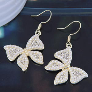 Detail of golden butterfly earrings with delicate white pearls and sparkling rhinestones