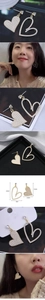 Close-up of asymmetrical gold heart earrings with white pearls and size measurements