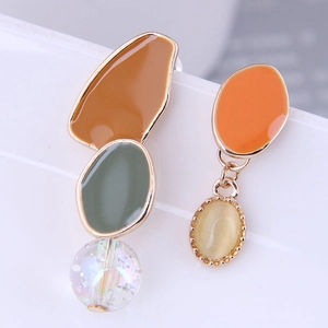 Detail of asymmetric earrings with colorful enamel patches and beads on a gold frame