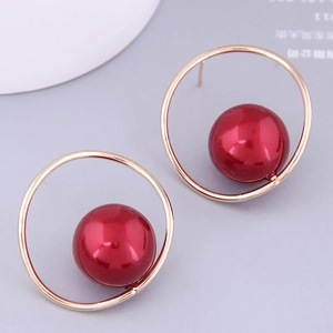 Detail of red pearl earrings featuring a golden circular metal frame for women