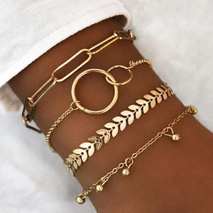 Set di quattro bracciali geometrici dorati con catene a graffetta e ciondoli a foglia