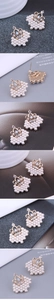 Detailed view of gold crown earrings with faux pearls, rhinestones and opal stone inlay
