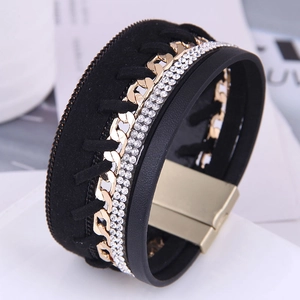 Détail d'un bracelet multicouche en cuir noir avec chaîne gourmette dorée et strass brillants