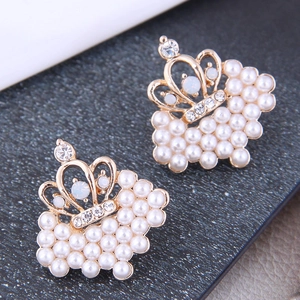 Close-up of crown shaped gold earrings with elegant white pearls and tiny crystals