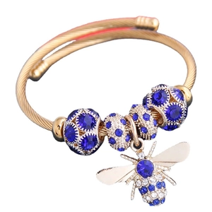 Golden wrap bangle featuring blue crystal beads and an intricate bee pendant design