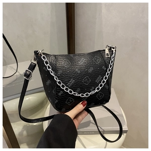 Détail du sac seau en cuir noir texturé avec chaîne argentée et motif d'ours