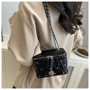 Macro detail of black quilted mini bag featuring silver rose pendant and metal chain