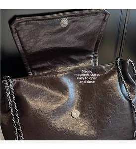 Close-up of a magnetic buckle closure on a brown textured leather shoulder bag