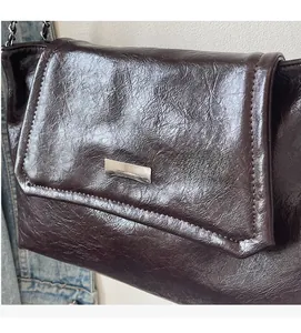 Detail of vintage dark brown chain bag with wrinkled patent texture and silver buckle