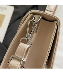 Close-up of adjustable strap with silver hardware on beige square crossbody bag