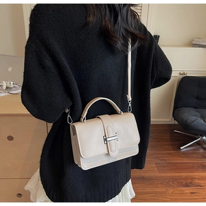 Chic beige leather crossbody bag showcased by a model against a black knit sweater