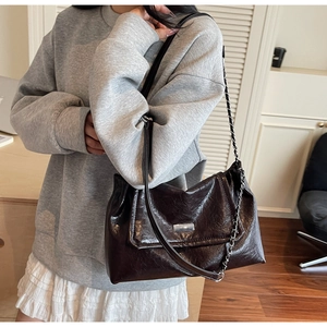Detail view of dark brown oil wax shoulder bag featuring silver chain and metal clasp