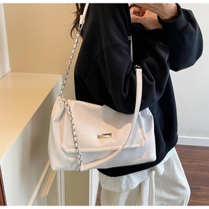 Close-up of white leather tote with gold metal plate and woven chain strap on model