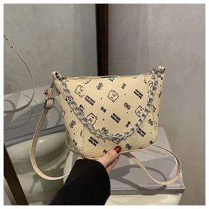 Gros plan du sac seau beige avec motifs d'ours et bandoulière chaîne argentée