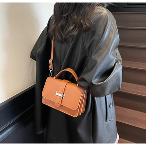 Detail of caramel leather crossbody bag featuring iconic metal H buckle and pleated sides