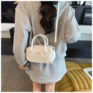 Chic white lace mini bowling bag featuring silver bow charm shown on a casual model