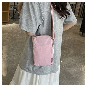 Detailed side view of a pink crossbody phone bag worn by a model in casual attire