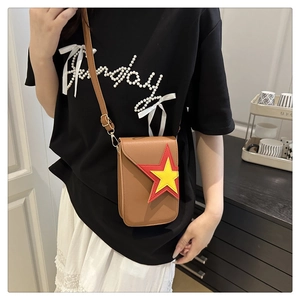 Détail d'un sac bandoulière en cuir marron avec un motif étoile rouge et jaune