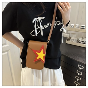 Detail of a brown leather crossbody bag with red and yellow star patchwork and slim strap