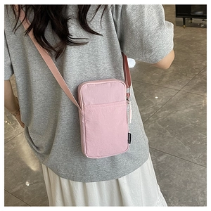 Pink crossbody phone bag with adjustable strap and fashion label shown on model back