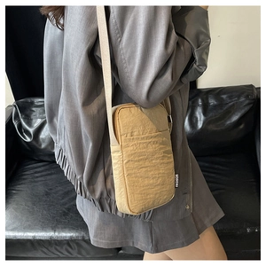 Detail of beige wrinkled nylon phone crossbody bag showing fashion tag and strap