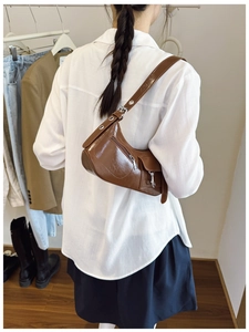 Détail du sac hobo marron brillant avec boucles argentées et œillets métalliques rétro