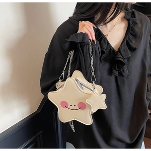 Dettaglio della borsa a tracolla beige a forma di stella con viso sorridente e catena